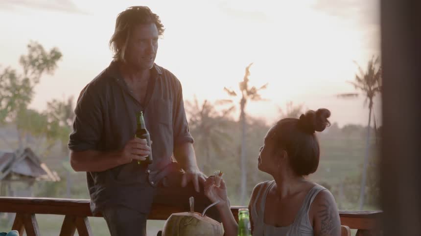 People sit outside at table talking and drinking beer
