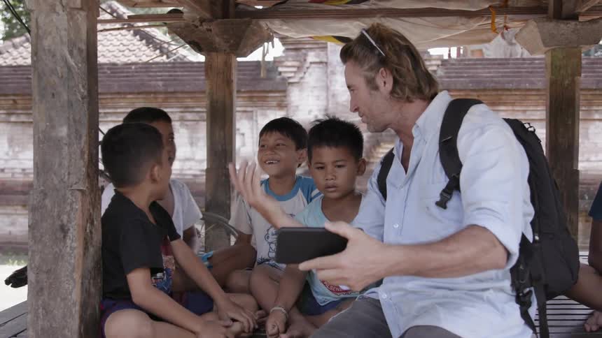 Man shows his phone to young boys