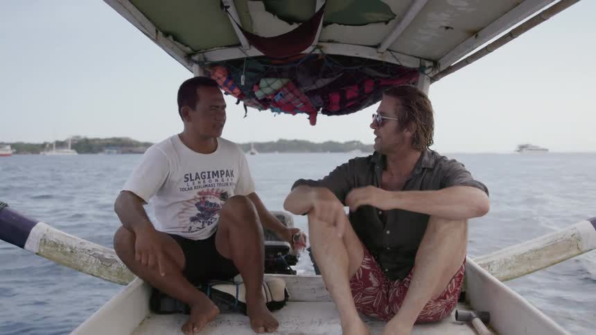 Two men sit and talk while riding on a small boat