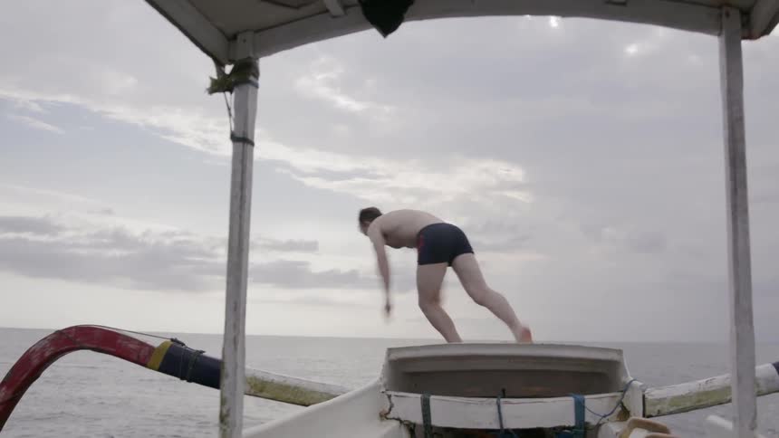 A man dives from a boat into ocean water