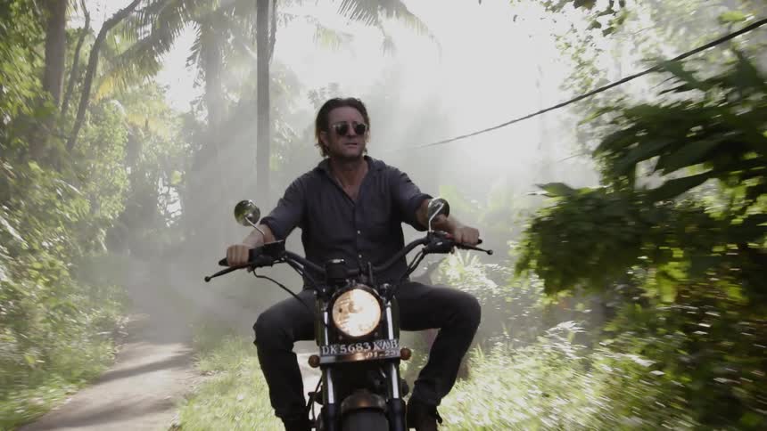 Man drives motorcycle along jungle road