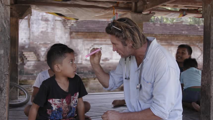 A physician examines boys in a village