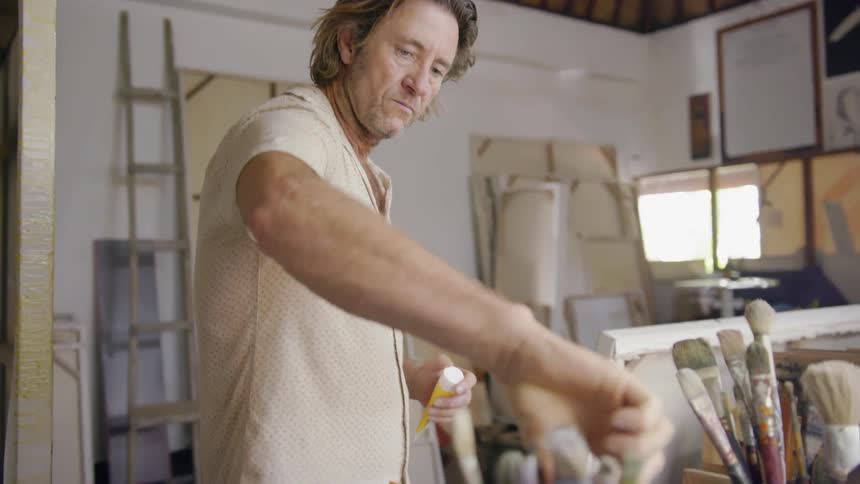 An artist grabs a brush from a bucket