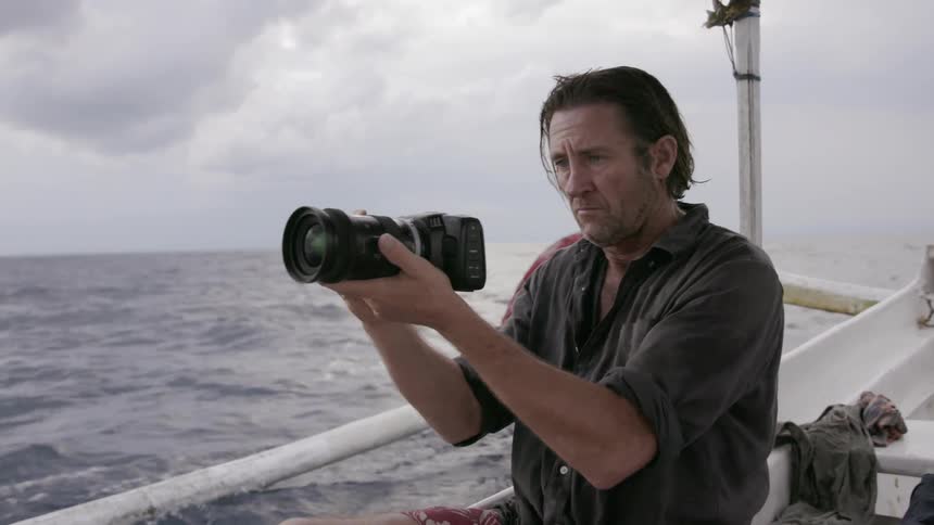 Man sitting on a boat taking pictures of the water