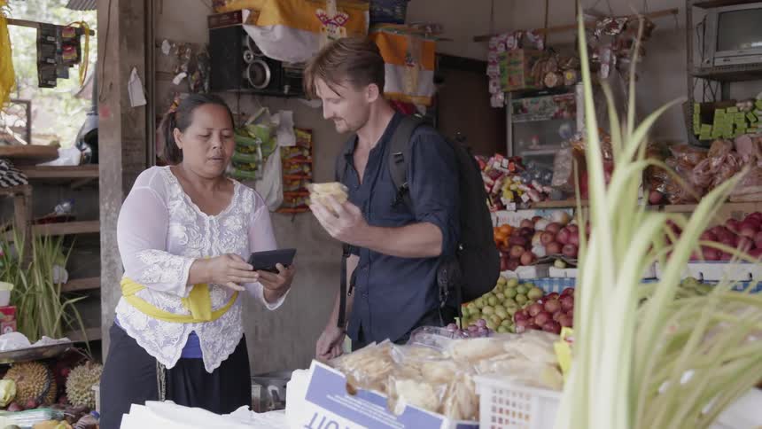 A woman shows a man a total on a calculator as he selects goods