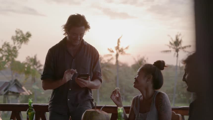 A man uses a cell phone while dining with people