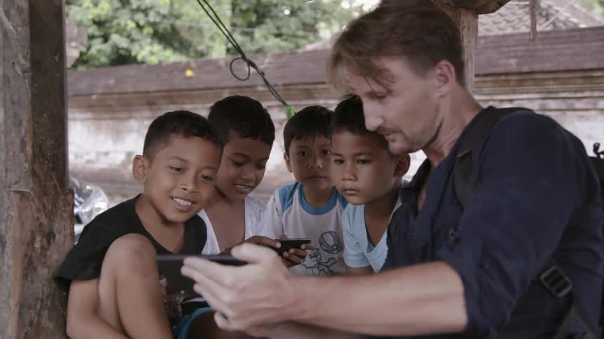 A man shows young kids his phone