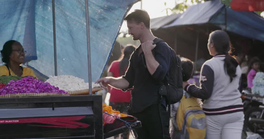 A man points at flowers and describes what he wants to the woman at the flower cart