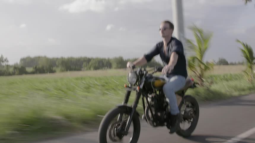 A man motorcycles on a rural road