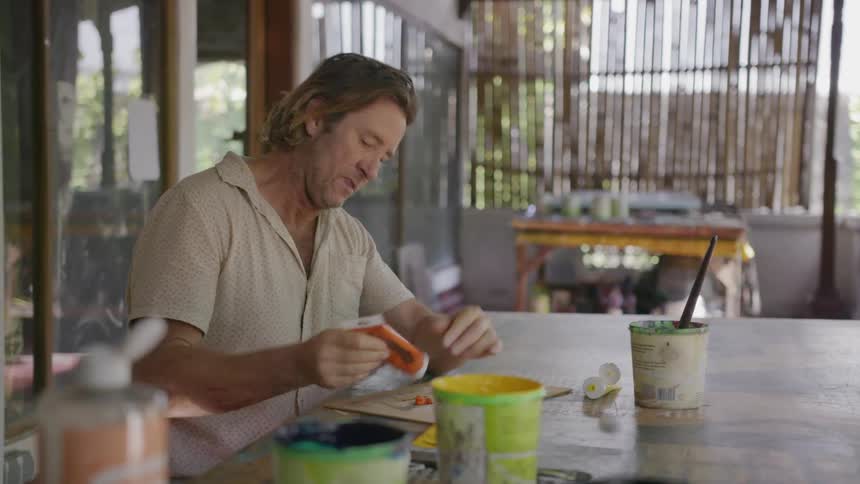 Man sits at a table squeezing paint onto a palette