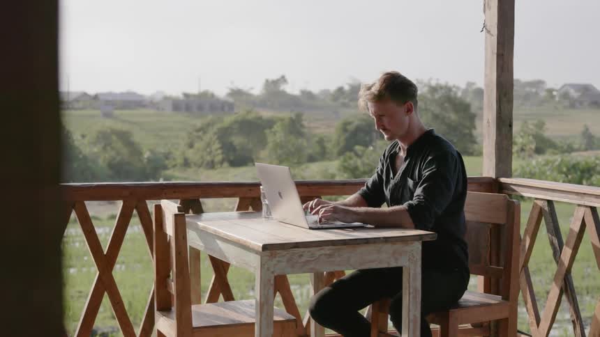 A man uses a laptop outside