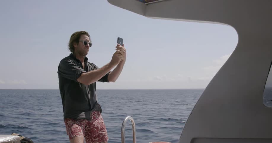 A man takes a selfie from a boat