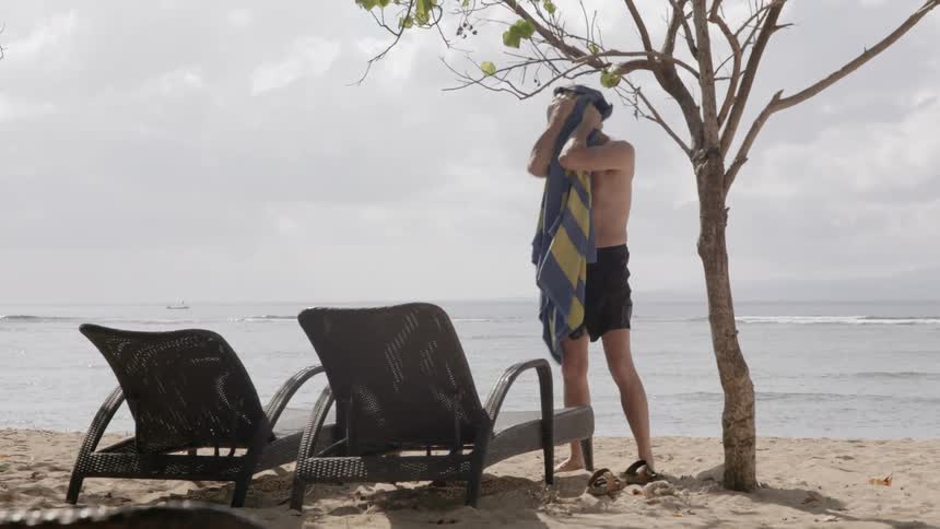 A man dries himself off with a towel on the beach