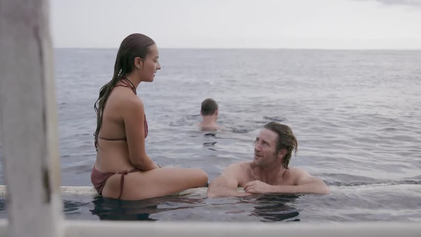 A man talks to a woman sitting on a floating pipe
