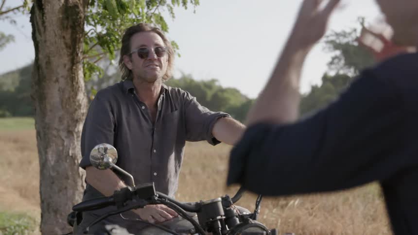 Two men talk while sitting on parked motorcycles