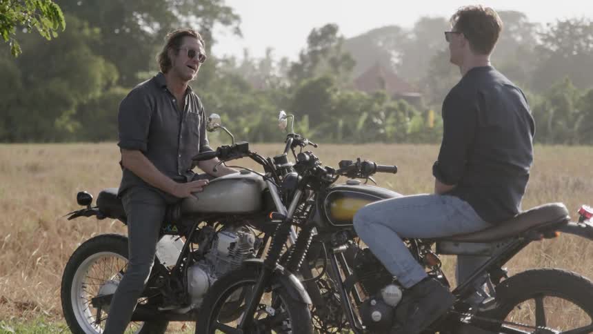 Two men talk on motorcycles