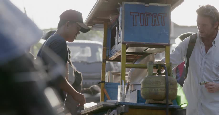 A man is looking at food from a street vendor