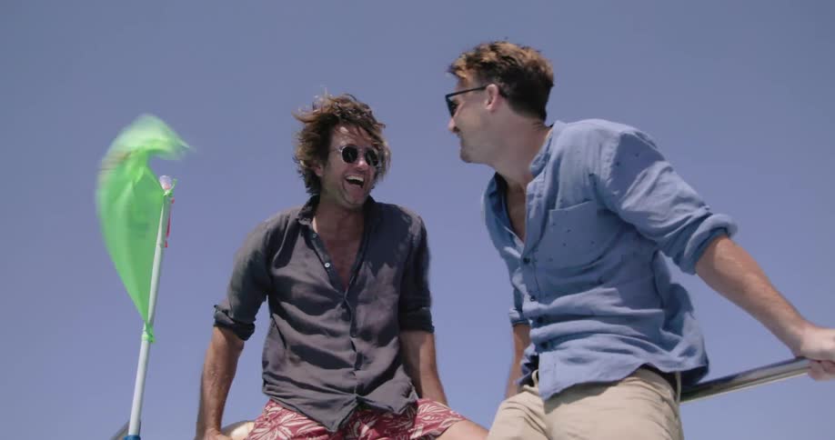 Two men laugh outside on a windy day