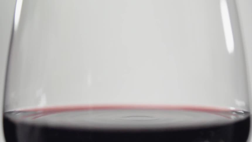 A drop of wine splashes in a wine glass