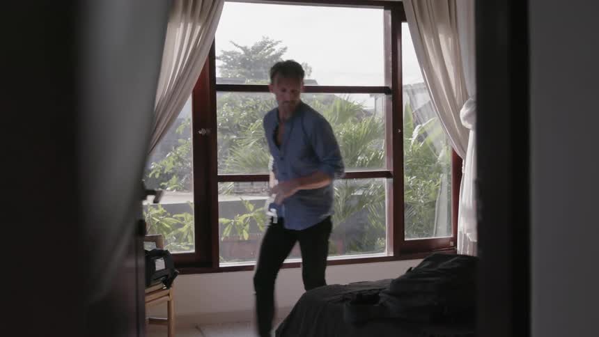 A man styles his hair in his bedroom