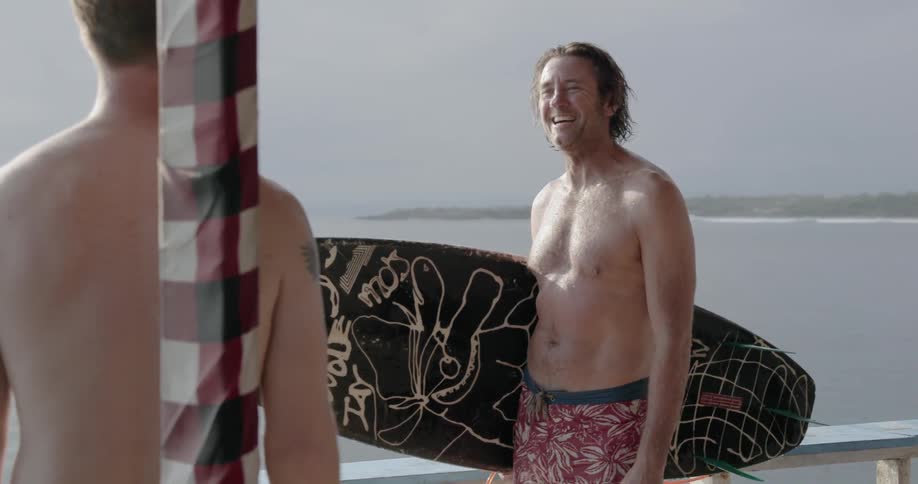 Man stands on a beach with a surfboard