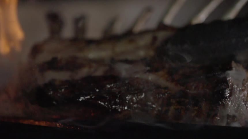 A rack of lamb is put on a flaming grill