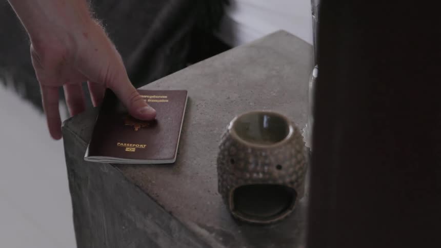 Person picks up a passport from a table