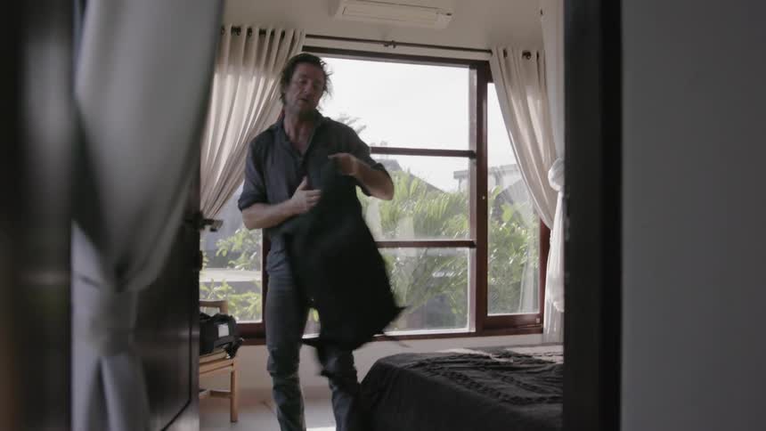 Man puts on shoes and picks up a backpack in a bedroom