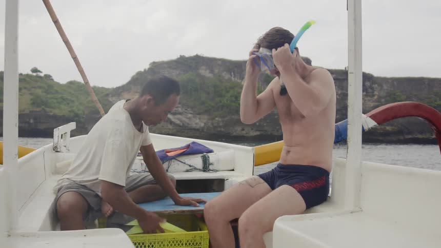 A man puts on a snorkel in a boat