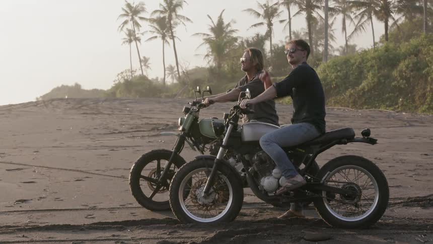 Two men riding on motorcycles on the beach