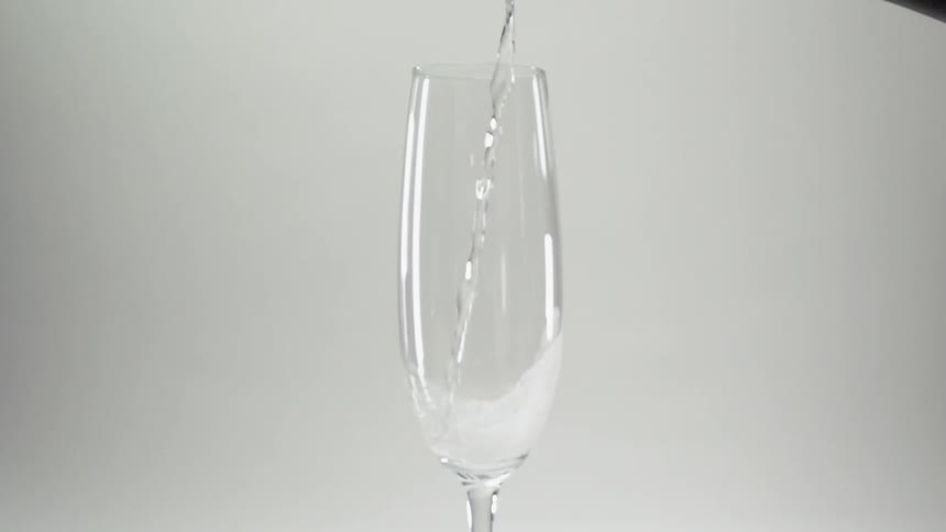 Water being slowly poured into a champagne glass
