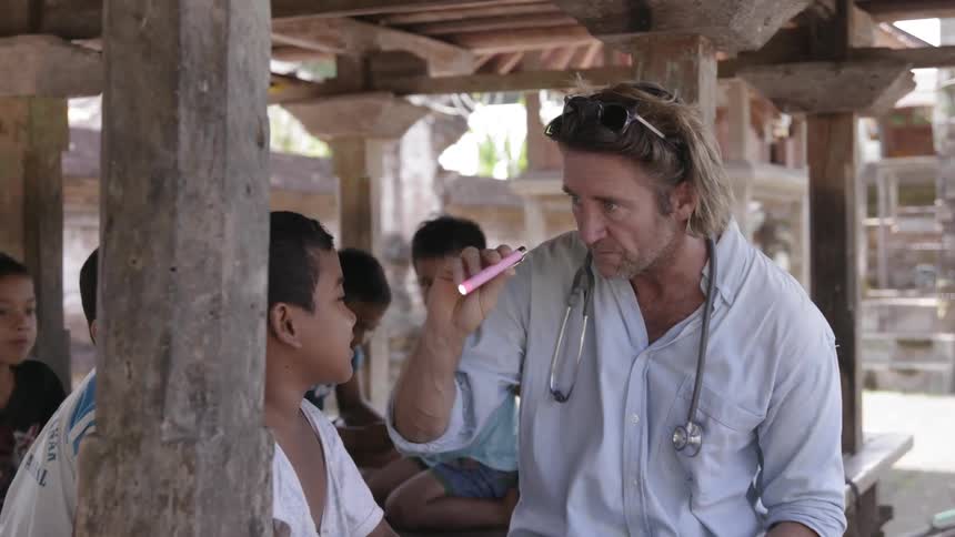 A physician examines boys in a village