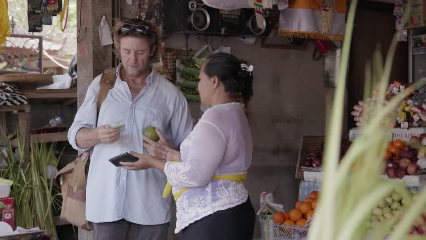 A shopkeeper shows a price to a customer who pays her in cash