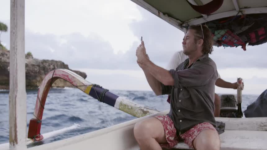 Man takes a photograph while riding in a boat