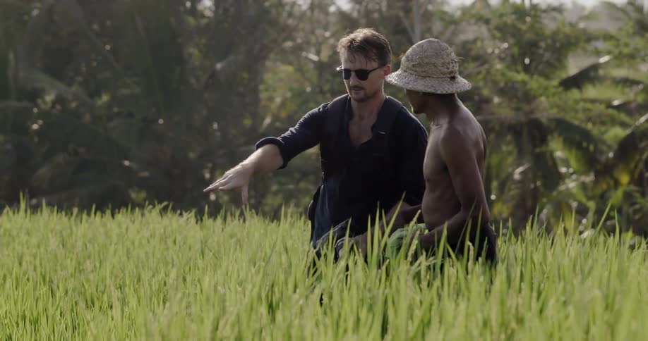 Two men talk in a grassy field