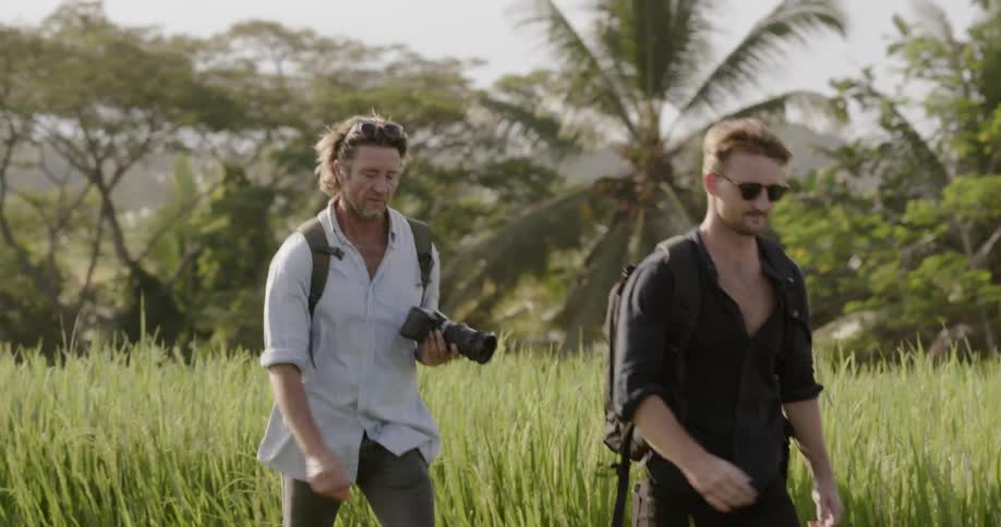 Two men hike in a grassy field