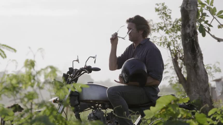A man sits on a parked motorcycle