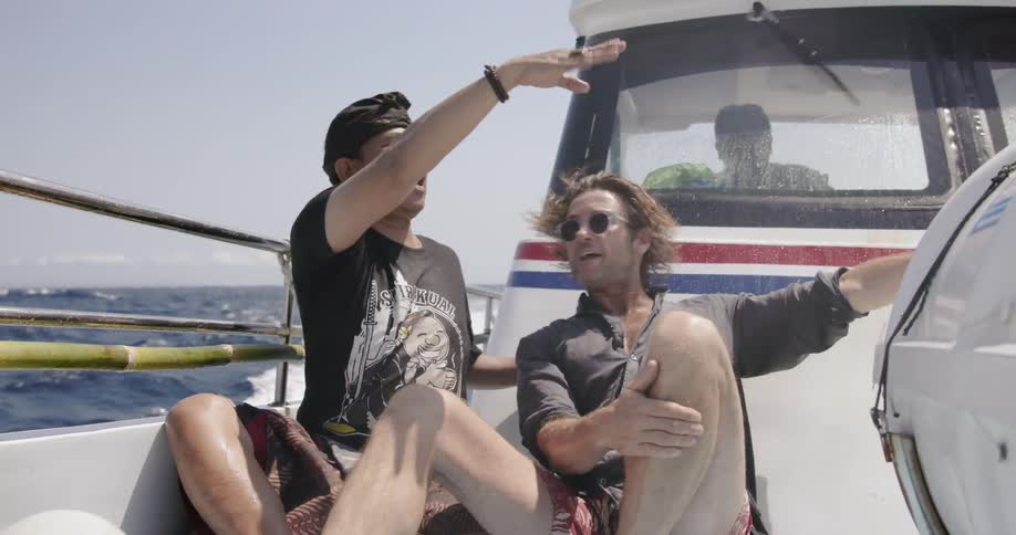 Two men ride and talk on a boat