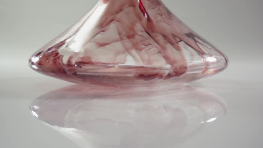Red liquid is poured into a shallow round glass