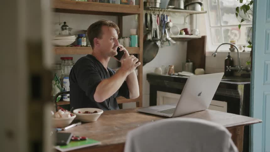 Man talks on the phone at a dining table