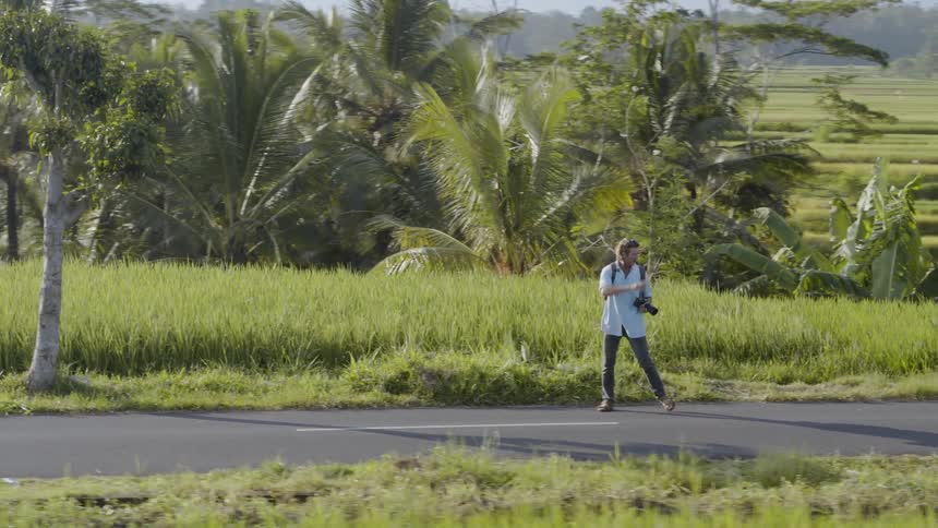 A man carries a camera while walking up hill