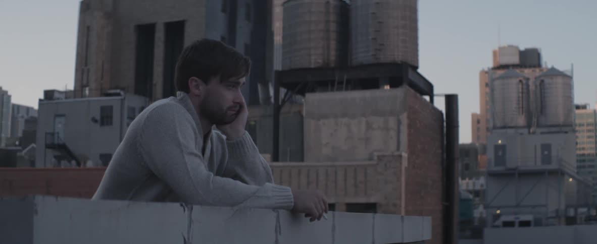 A man smoking a cigarette on a city rooftop