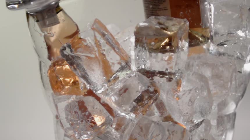 A bottle of beer is removed from a bucket of ice