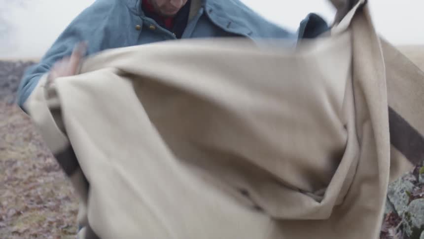A soldier shakes off a blanket outside