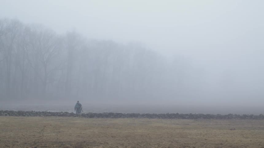 Man walks in a misty field