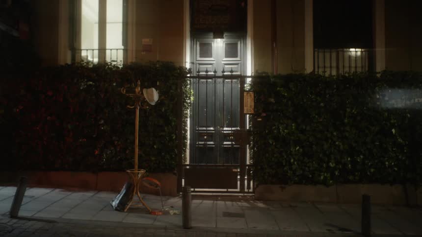 Coat tree outside of a house on the sidewalk at night