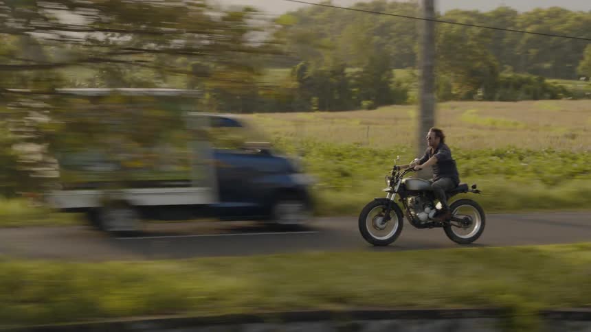 A man rides a motorcycle on a rural road