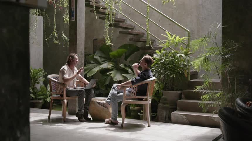 Two men sit in chairs as they talk