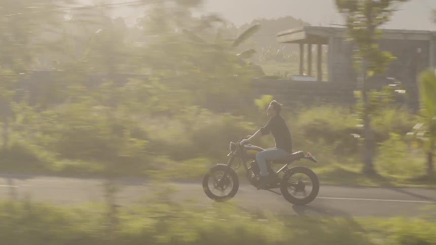 A man rides a motorcycle on a rural road
