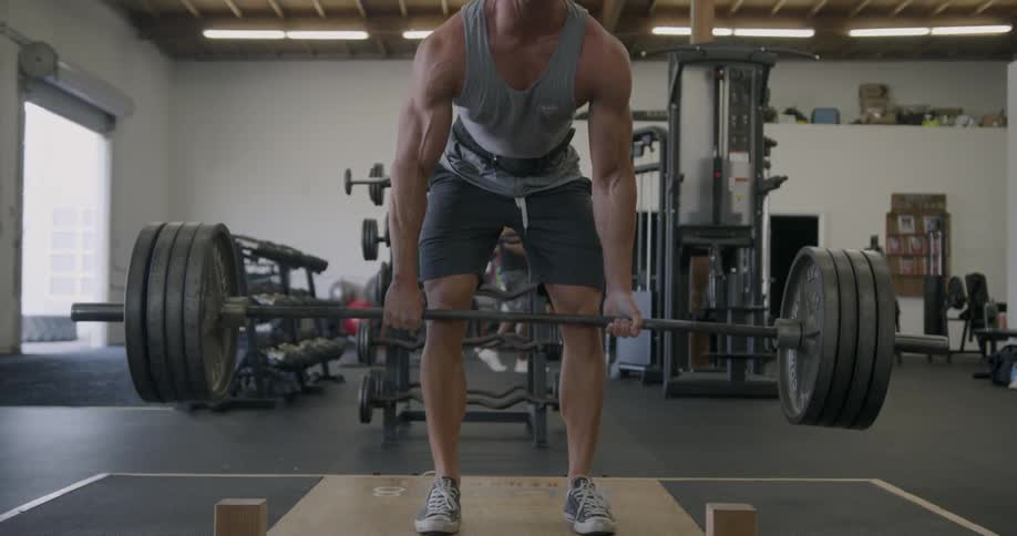 A man squats some weights in the gym